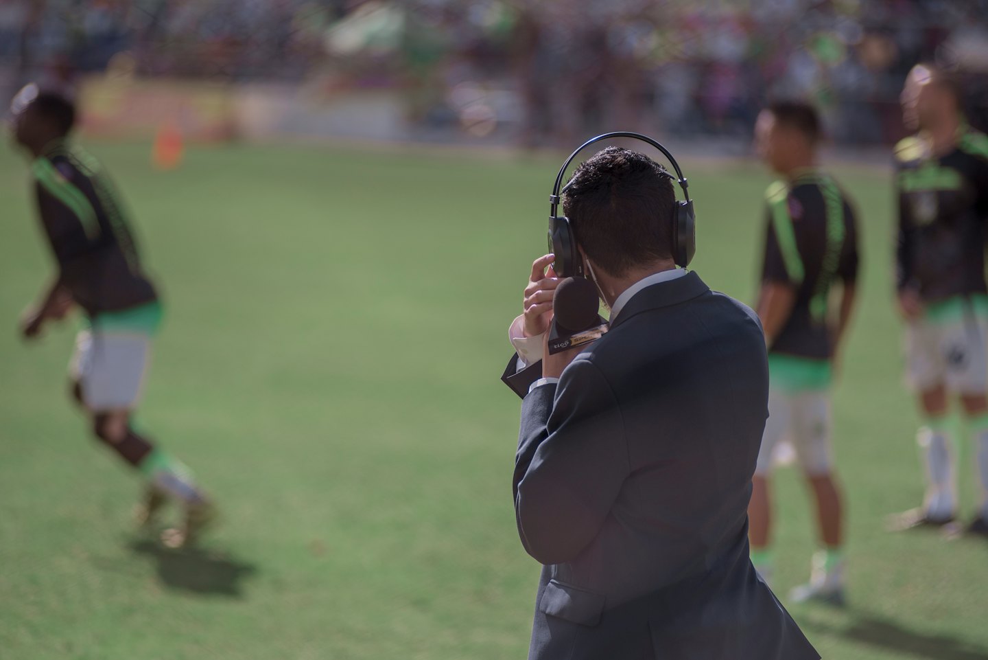 Reporter with headphones and microphone watches a game.