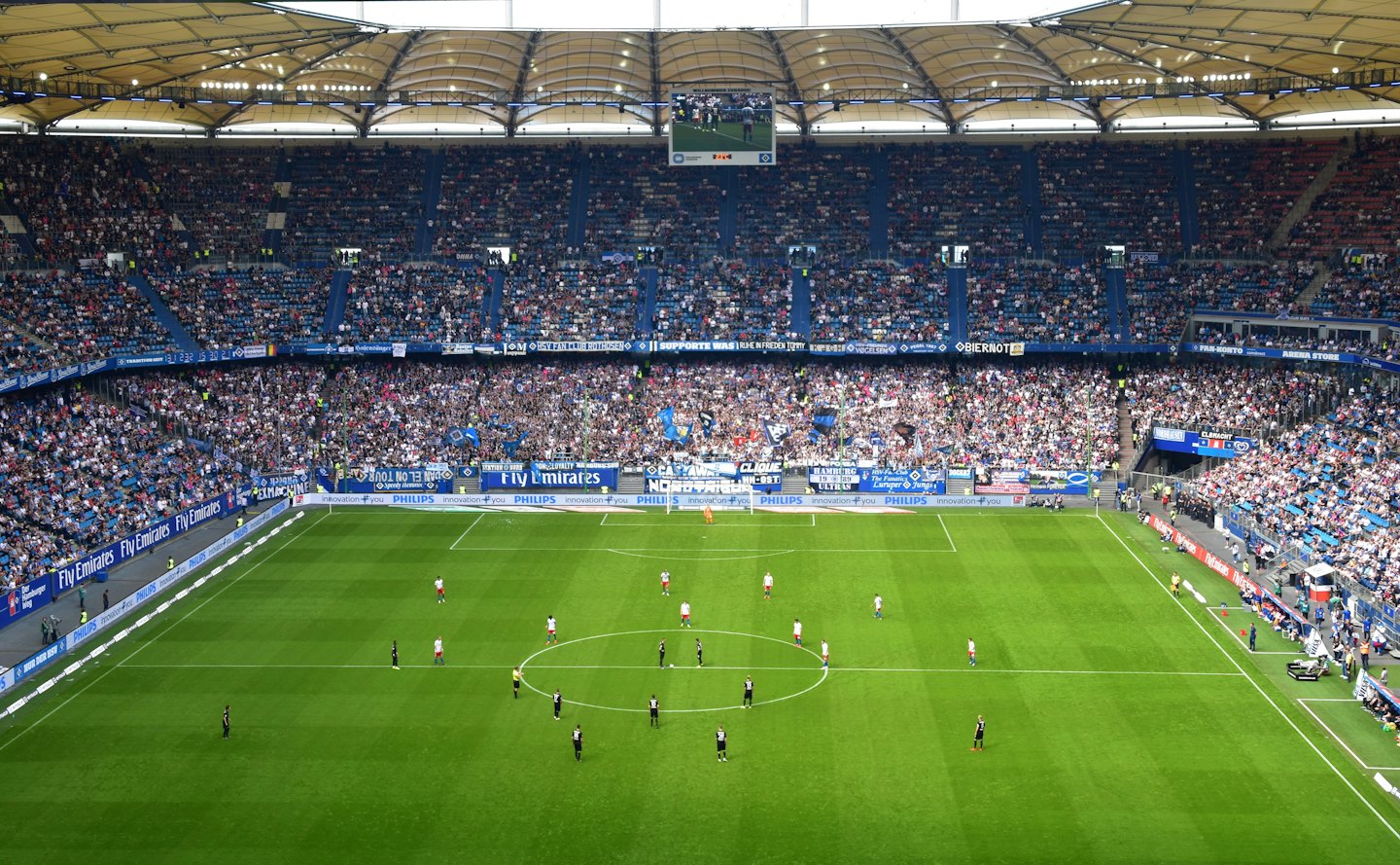 Soccer players on a green field in a large stadium.