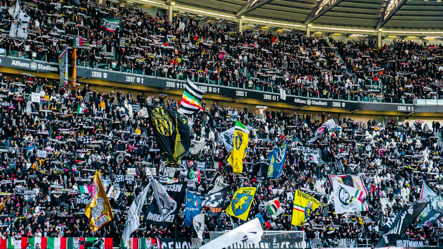Crowd of football fans waving flags inside Allianz Stadium.